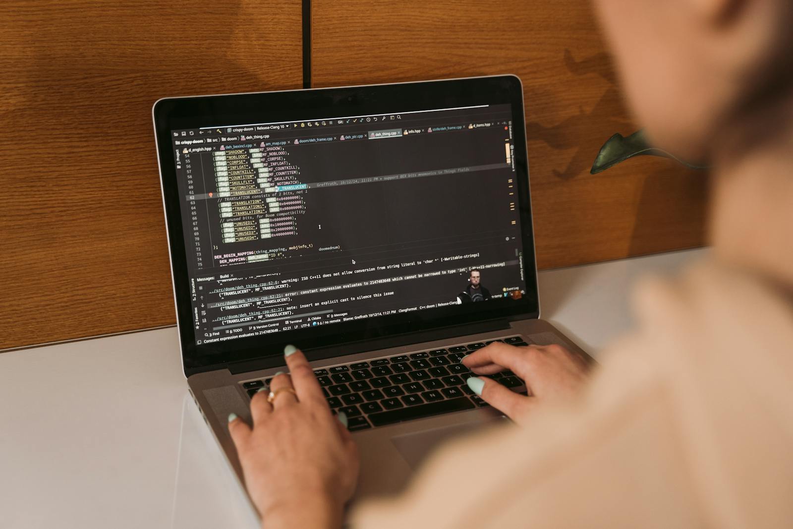 Close-up of a woman coding using a laptop in an office environment, showcasing modern technology.